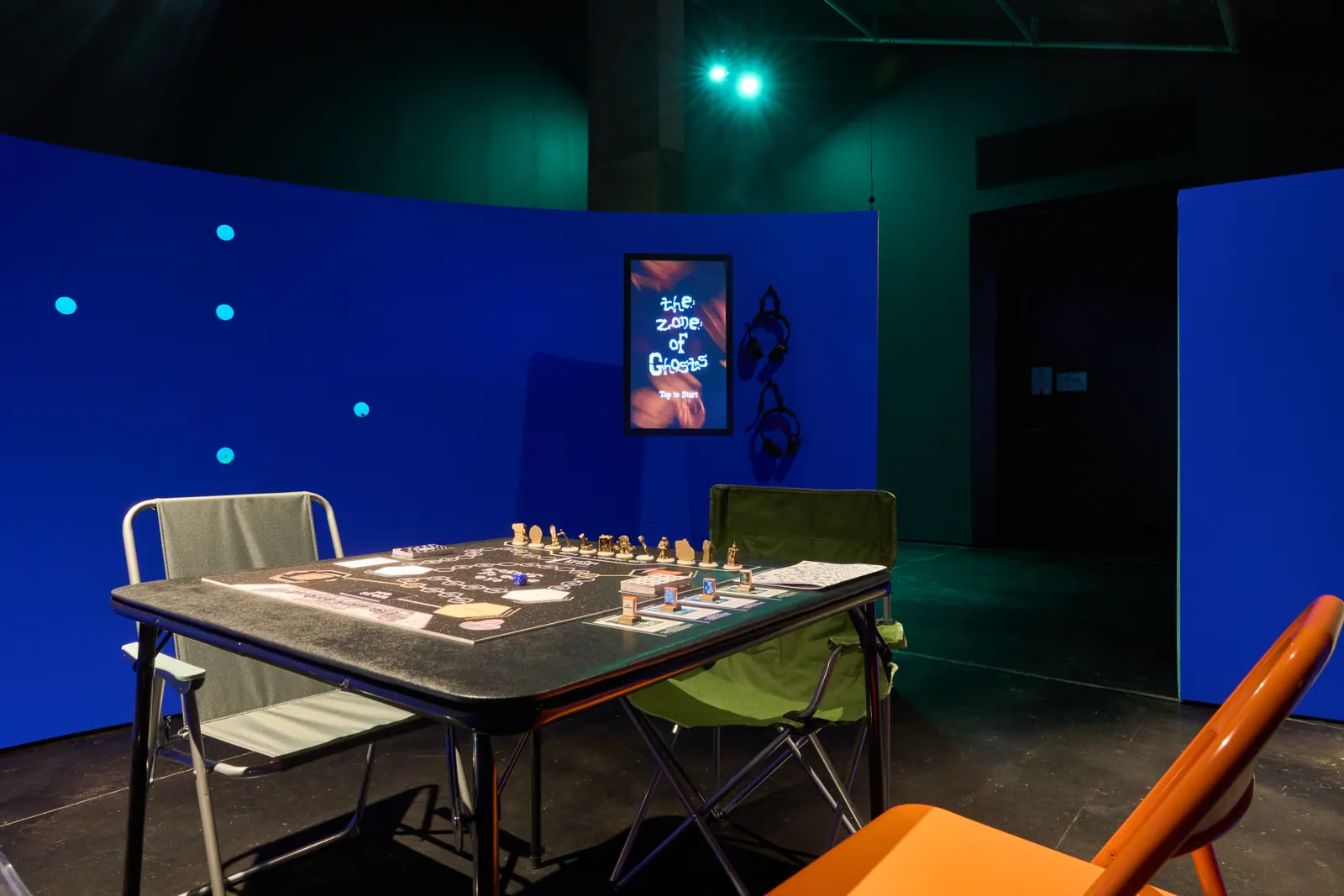 A table set up with The Zone of Ghosts board game inside a blue-lit section of the installation