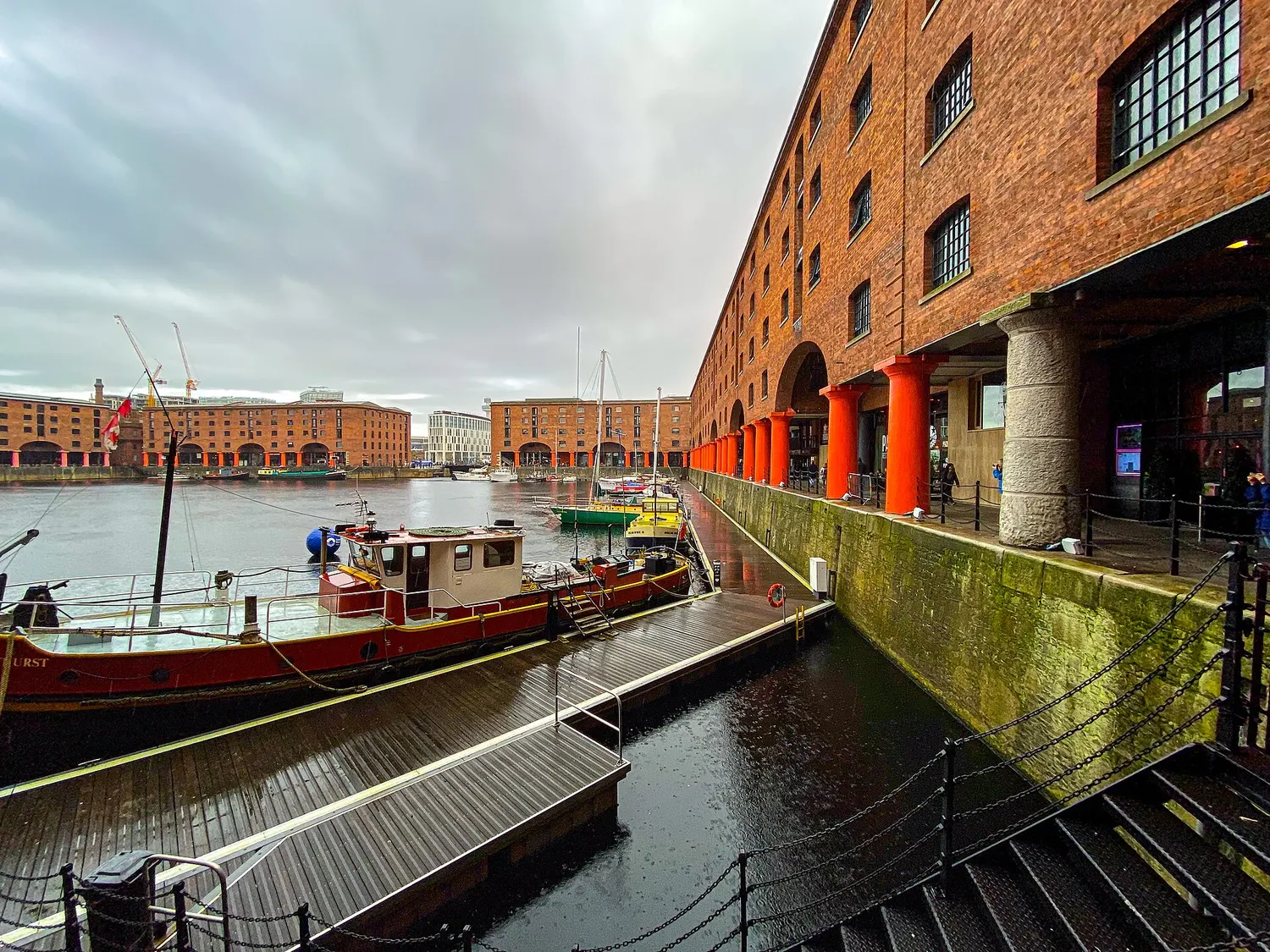 The brick warehouses of Royal Albert Dock reflected in the still water of the dock basin